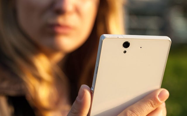 A blonde woman with a smug on her face looking at her phone, texting her ex