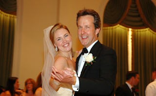 A father and his daughter dancing at the daughter's wedding while smiling