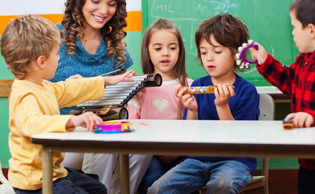 Kids and their teacher at kindergarten playing with musical instruments