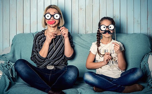 A mother who's not afraid of being a 'weird' mom and daughter sitting on a couch with mouth and glas...