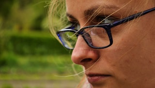 A woman with glasses who has developed resting bitch face in her old age