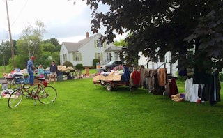 Different types of people at a yard sale with a lot of things displayed there