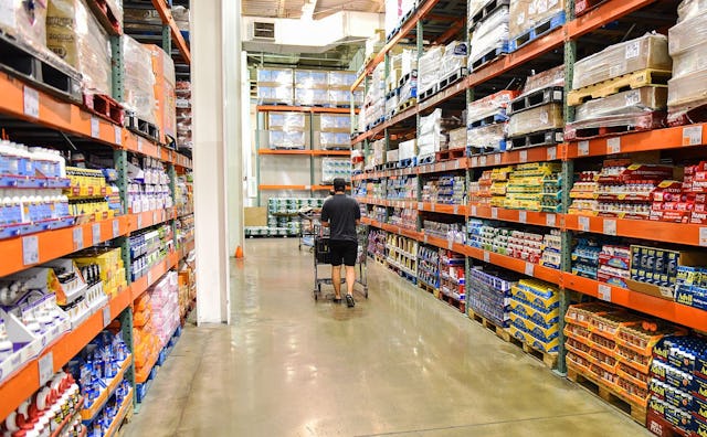Interior of a storage looking supermarket named Costco with shelves filled to the brim and a person ...