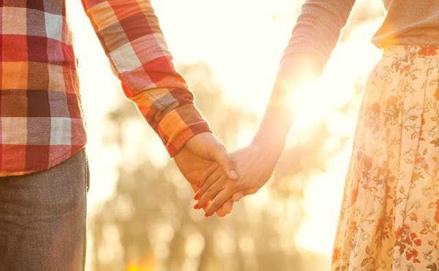 A couple holding hands on a date with a sunset in the background