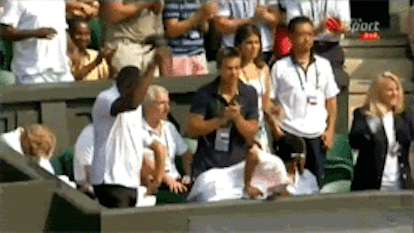 An audience watching a tennis game and cheering 