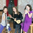 Two girls singing songs that helped their mom and dad parent in their 40s and one playing acoustic g...