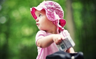 A baby girl wearing a pink cap and shirt just like her mommy