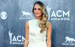 Carrie Underwood in a white fringed dress at the ACM Awards standing and posing