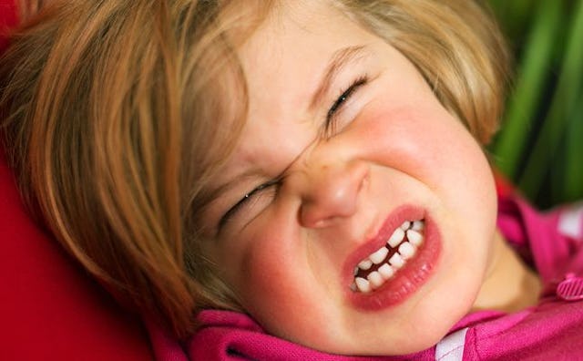 A toddler crying with a frustrated look on her face.