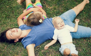 A mother lying on the grass with her two kids
