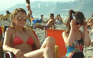 Two girls in the 80s at a crowded beach