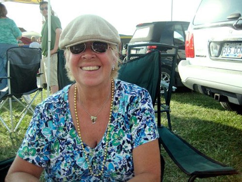 A woman in a blue shirt and sunglasses sitting on a camping chair and smiling 