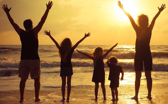 Family of 5 at the beach facing the sun at the golden sunset.
