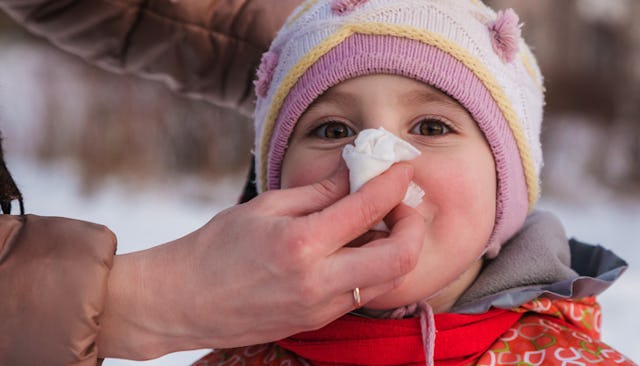 A close-up of a woman wiping a child's nose during daycare