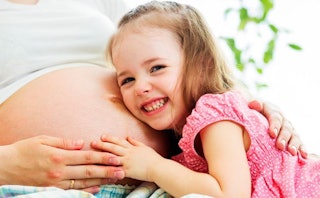  A daughter putting her head on mother's pregnant belly