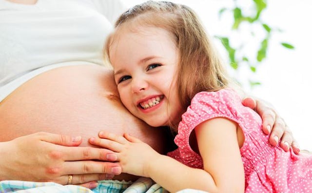  A daughter putting her head on mother's pregnant belly