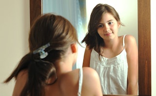 Teenage girl looking herself in the mirror