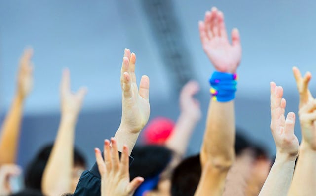 A close-up of multiple hands lifted in the air representing volunteerism