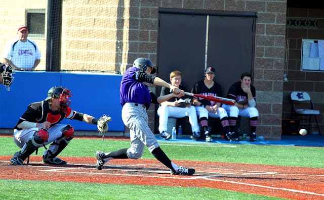 Two baseball players, one hit the ball with his bat, and the other one trying to catch it, players s...