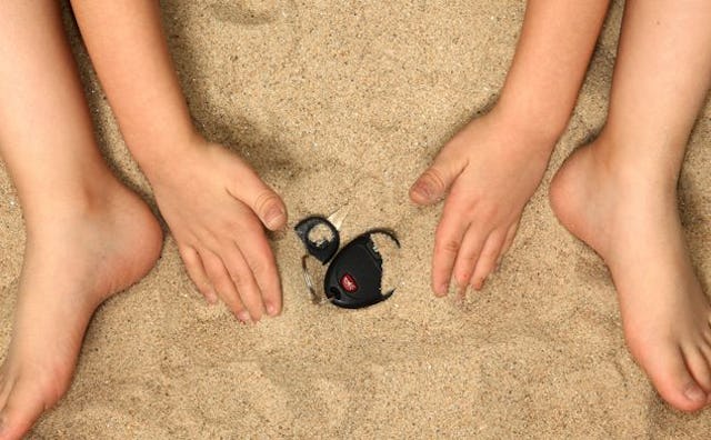 A child hiding car keys in the sand