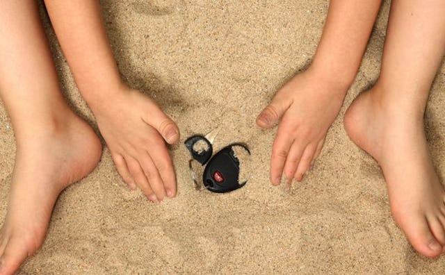  A child hiding car keys in the sand 