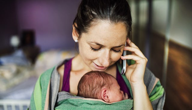 A new mom talking on the phone while holding her newborn child