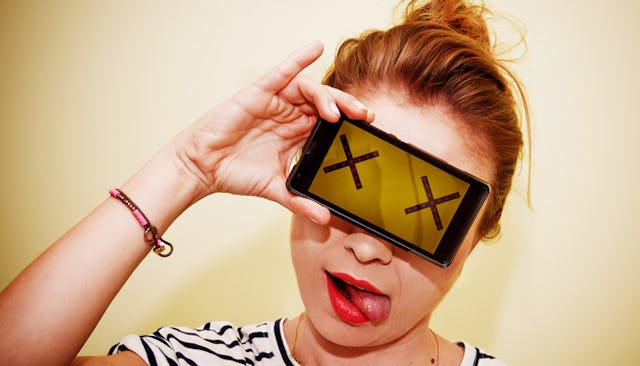 A young girl holding a phone in front of her eyes with two x signs and didn't answer the phone