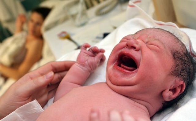 A newly born baby crying in a hospital following delivery.