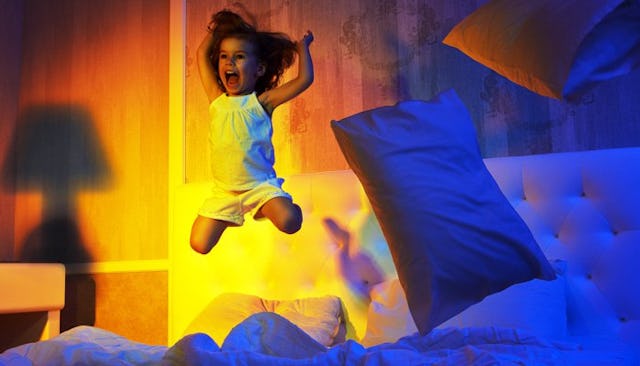 A small girl jumping and screaming on a toddler bed