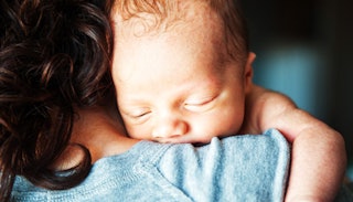 A mother holding her newborn sleeping baby on her shoulder