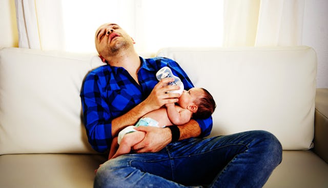 An expecting dad in a blue-black checkered shirt and jeans sleeping while holding his toddler and fe...