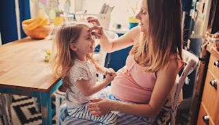 Exhausting pregnant mother with her toddler sitting on her lap 