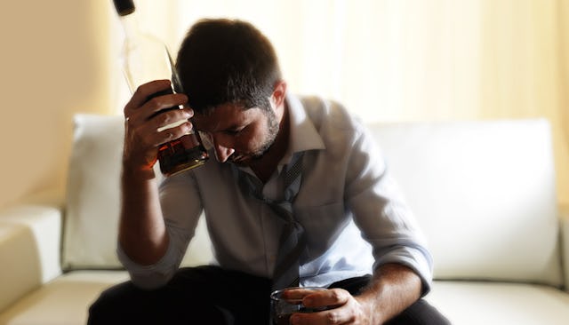 Man sitting on the couch and drinking a bottle of whiskey