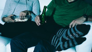 A married couple celebrating their wedding anniversary with popcorn and beer on a couch