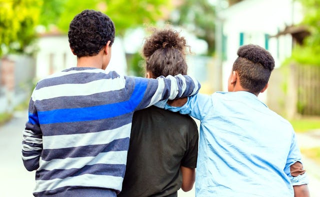Two grandchildren hugging their grandmother, while walking down the street