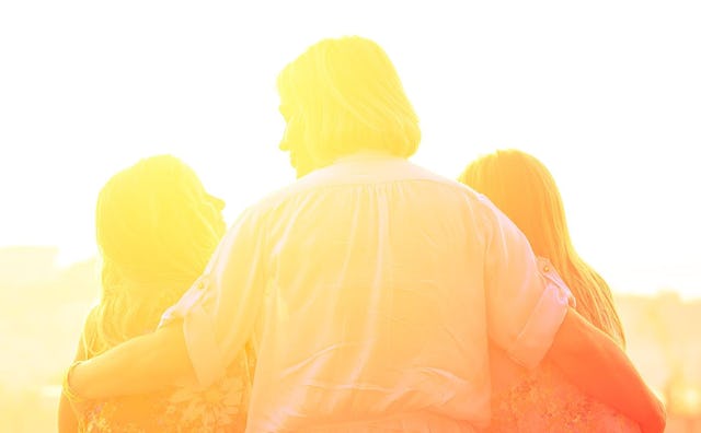 A senior year person standing between her two friends and hugging them with a yellow color filter