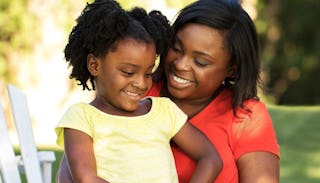 A mother smiling while holding her daughter in her lap