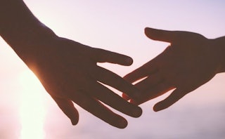 Image of a couple separating hands with the sun in the background