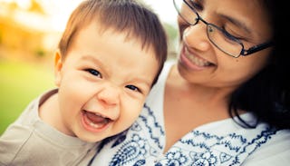 A single mom holding her baby boy while he is smiling to the camera.