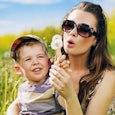 A mother and her son sitting in a meadow, blowing dandelions as divorce has made her a better mom 