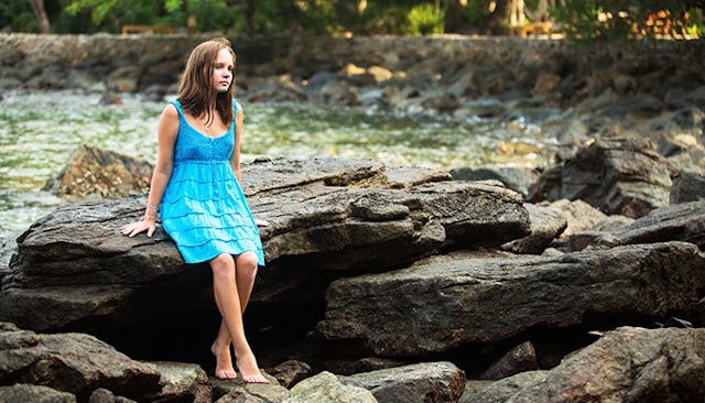 teen-girl-standing-on-rocky-beach