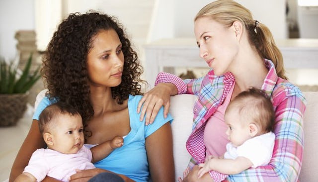 Two moms sitting and talking with their babies on their laps