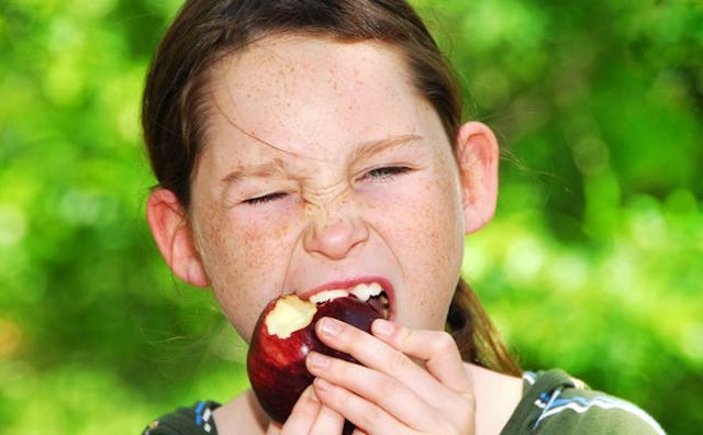 Girl with brown hair biting an apple