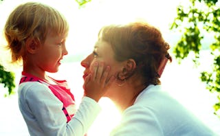 A smiling daughter looking at her mother with her hands on her mother's face