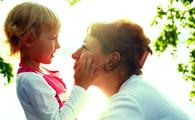 A smiling daughter looking at her mother with her hands on her mother's face