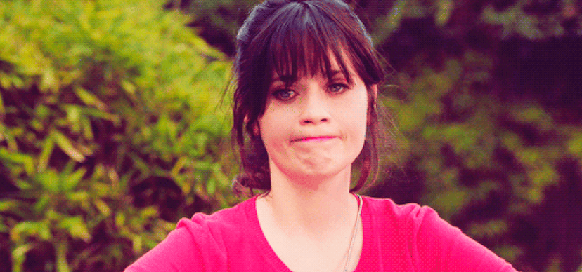 Gif of actress Zooey Deschanel with her hair tied up and wearing a pink shirt while nodding