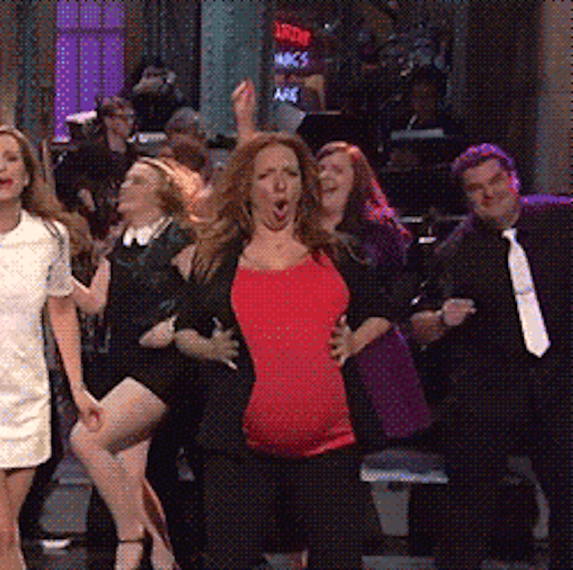 Gif of actress Maya Rudolph wearing a red shirt while pregnant, with her and people behind her danci...