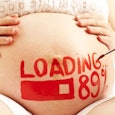 Pregnant woman's belly with her arms on it and someone writing in red text "loading 89%"