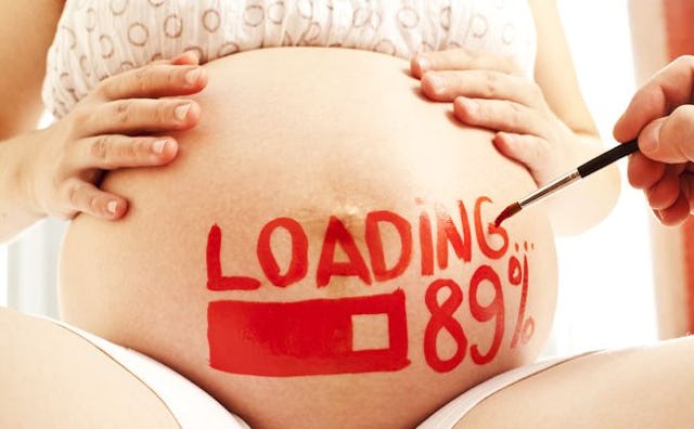 A pregnant woman's belly with her arms on it and someone writing in red text "loading 89%"