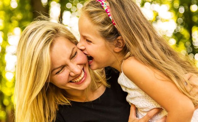 A woman and her daughter playing with each other while having big smiles on their faces
